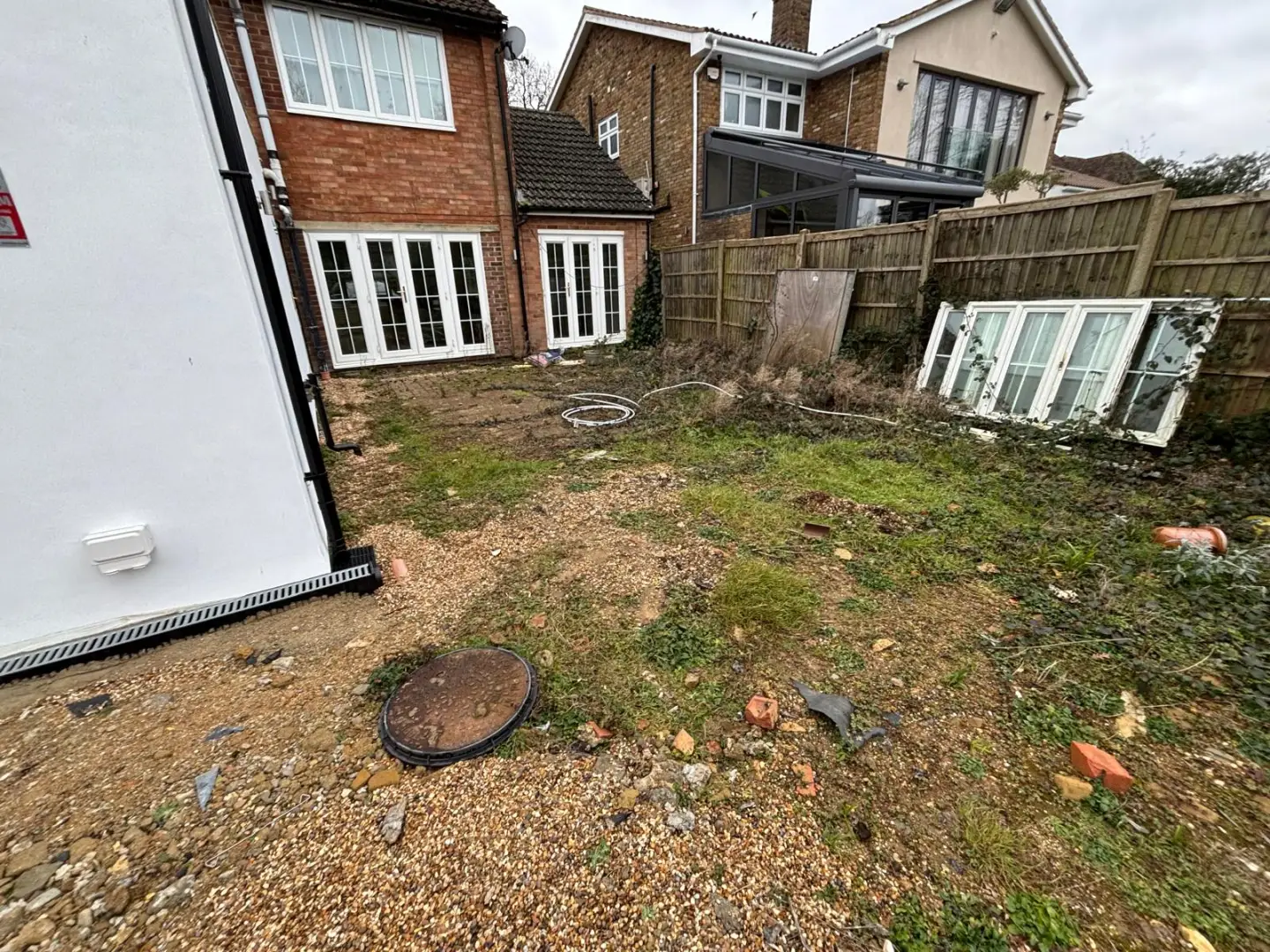 Existing rear garden beside the house before works, with uneven ground and no defined outdoor area