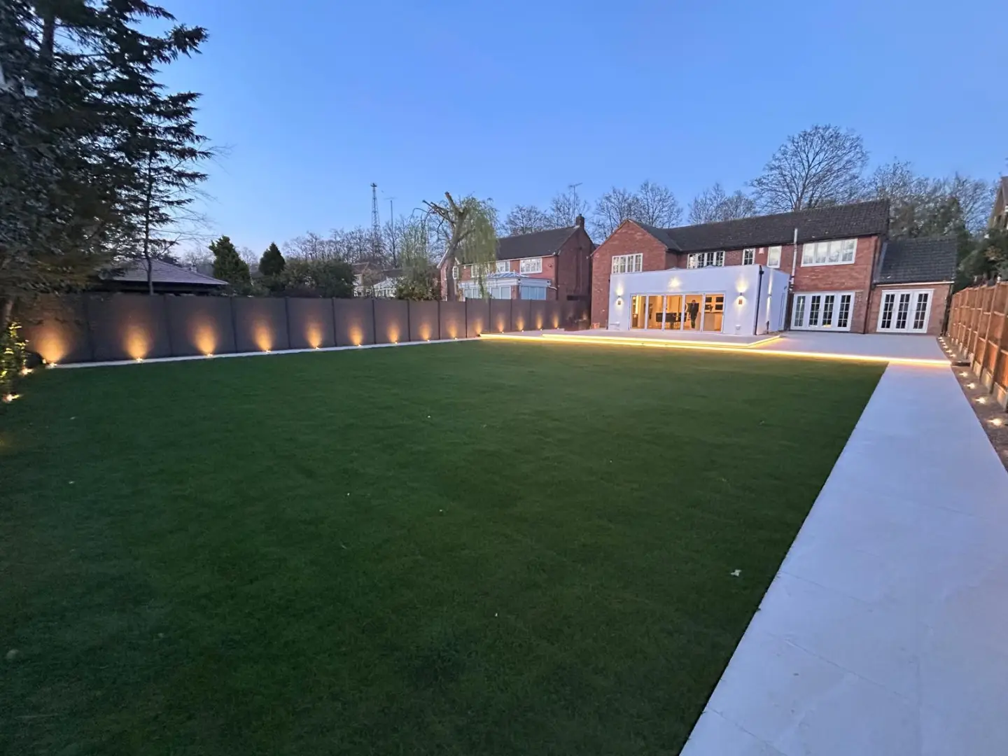 Completed garden at dusk with the new lawn, paved walkway and illuminated boundary