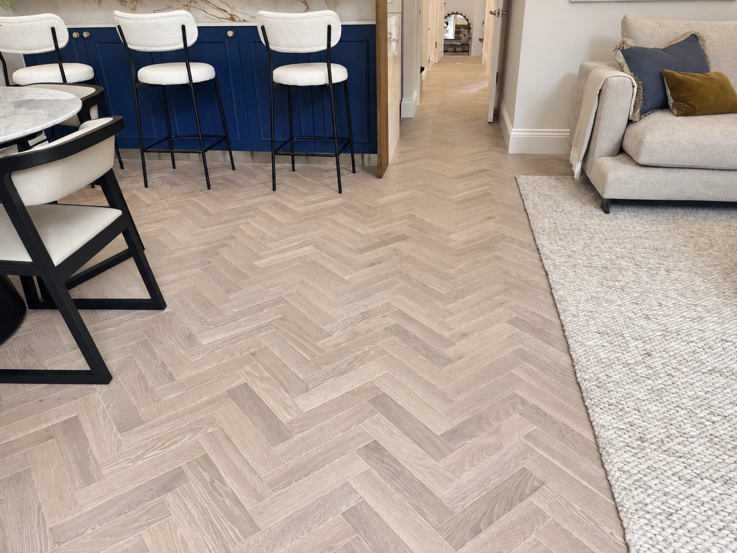 Herringbone timber floor leading to open-plan living and navy kitchen island